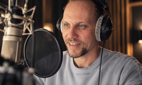 Nik Thomi mit Kopfhörern vor seinem Neumann TLM 103 in seinem Aufnahmestudio
